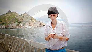 Young woman using cellphone on bay with motorboats