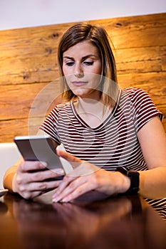 Young woman using cellphone at table