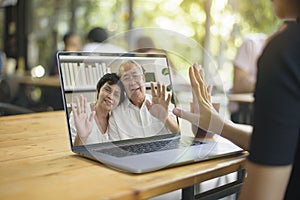 Young woman is using computer laptop to Video calling or Webcam to grandparent ,  telecommunications technology , parenthood