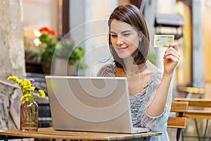 Young woman using credit bank card laptop computer while transferring money order food in cafeteria