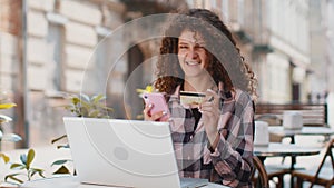 Young woman using credit bank card smartphone while transferring money order food in cafeteria