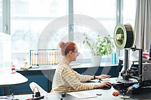 Young Woman using 3D Printer Side View