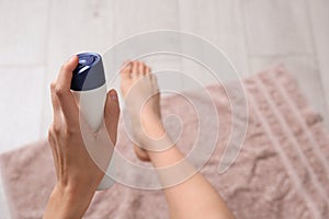 Young woman using deodorant for feet at home