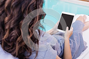 Young woman using digital tablet near poolside