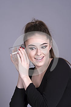 Young woman using a drinking glass as a hearing aid