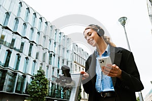 Young woman using electric scooter while standing at city street