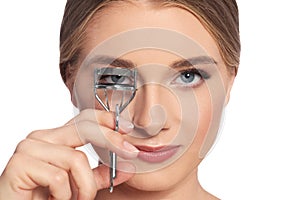 Young woman using eyelash curler on background, closeup