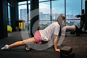 Young woman using a foam roller while doing stretching exercises
