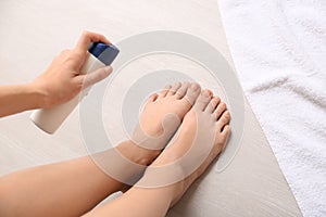 Young woman using foot deodorant at home