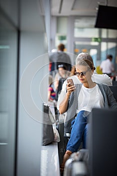 Young woman using her cell phone while waiting to board a plane at departure gates