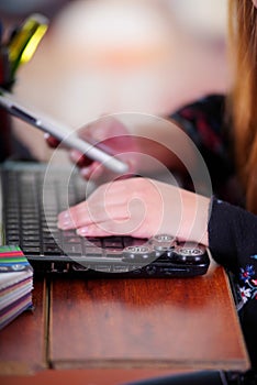 Young woman using her cellphone in the office and a popular fidget spinner toy over the laptop, on office background