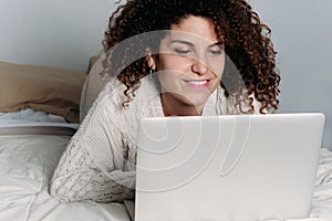 Young woman using her laptop on bed