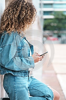 Young woman using her mobile phone outdoors on the street.
