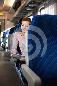 Young woman using her tablet  while traveling by train