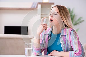 The young woman using inhalator to cope with asthma