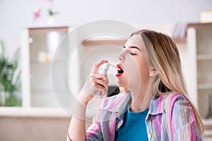 The young woman using inhalator to cope with asthma