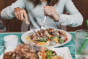 Young woman using knife and fork to cutting meat