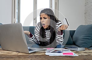 Young woman using laptop angry and stressed about her credit card bill