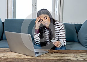 Young woman using laptop angry and stressed about her credit card bill