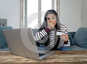 Young woman using laptop angry and stressed about her credit card bill