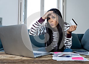 Young woman using laptop angry and stressed about her credit card bill