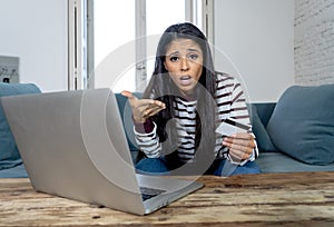 Young woman using laptop angry and stressed about her credit card bill