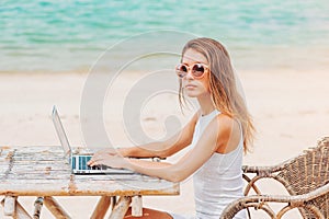 Young woman using laptop on the beach. Freelance work