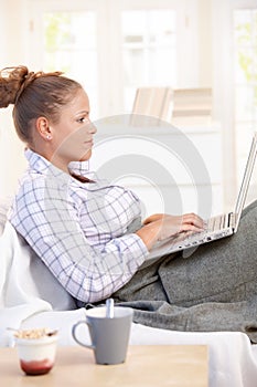 Young woman using laptop in bed at home