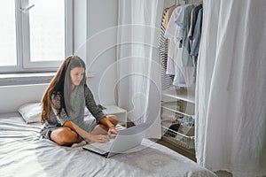 Young woman using laptop in the bedroom, freelance and home office concept