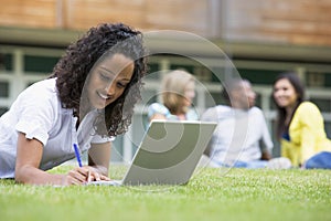 Young woman using laptop on campus lawn
