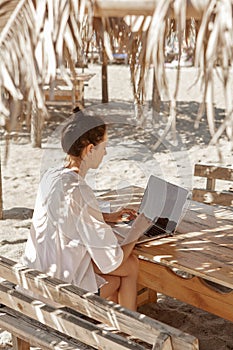 Young woman using laptop computer on a beach.