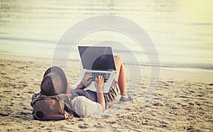 Young woman using laptop computer on a beach. Freelance work con