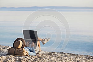 Young woman using laptop computer on a beach. Freelance work concept