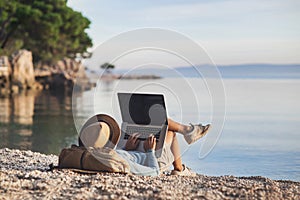 Young woman using laptop computer on a beach. Freelance work concept