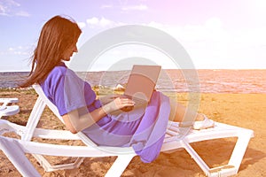 Young woman using laptop computer on a beach. Freelance work concept