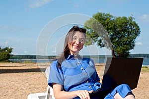 Young woman using laptop computer on a beach. Freelance work concept