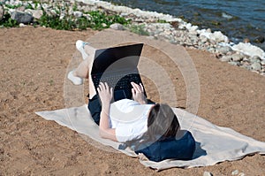 Young woman using laptop computer on a beach. Freelance work concept