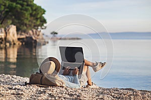 Young woman using laptop computer on a beach. Freelance work concept photo