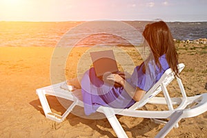 Young woman using laptop computer on a beach. Freelance work concept