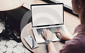 Young woman using laptop computer with blank white screen at cafe. Business woman working on computer in modern office.