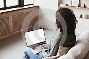 Young woman using laptop computer at home. Blank empty white mockup screen. Freelance, student lifestyle, online meeting concept