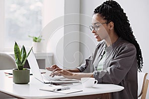 Young woman using laptop computer at office. Student girl working at home. Work or study from home, business concept