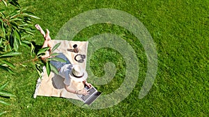 Young woman using laptop computer in park, student girl freelancer working and studying online outdoors sitting on grass