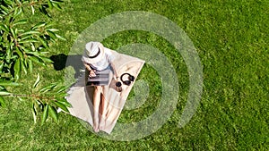 Young woman using laptop computer in park, student girl freelancer working and studying online outdoors sitting on grass