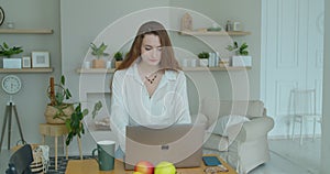 Young woman using laptop computer. Portrait of business woman watching news at laptop screen and drinking coffee at home