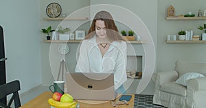 Young woman using laptop computer. Portrait of business woman watching news at laptop screen and drinking coffee at home