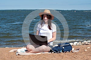 Young woman using laptop computer on sunbed on a beach. Freelance work concept, Freelancer outside