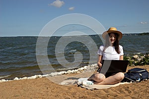 Young woman using laptop computer on sunbed on a beach. Freelance work concept, Freelancer outside