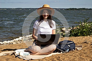 Young woman using laptop computer on sunbed on a beach. Freelance work concept, Freelancer outside