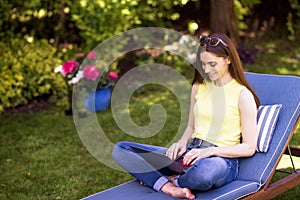 Young woman using laptop in the garden while working from home